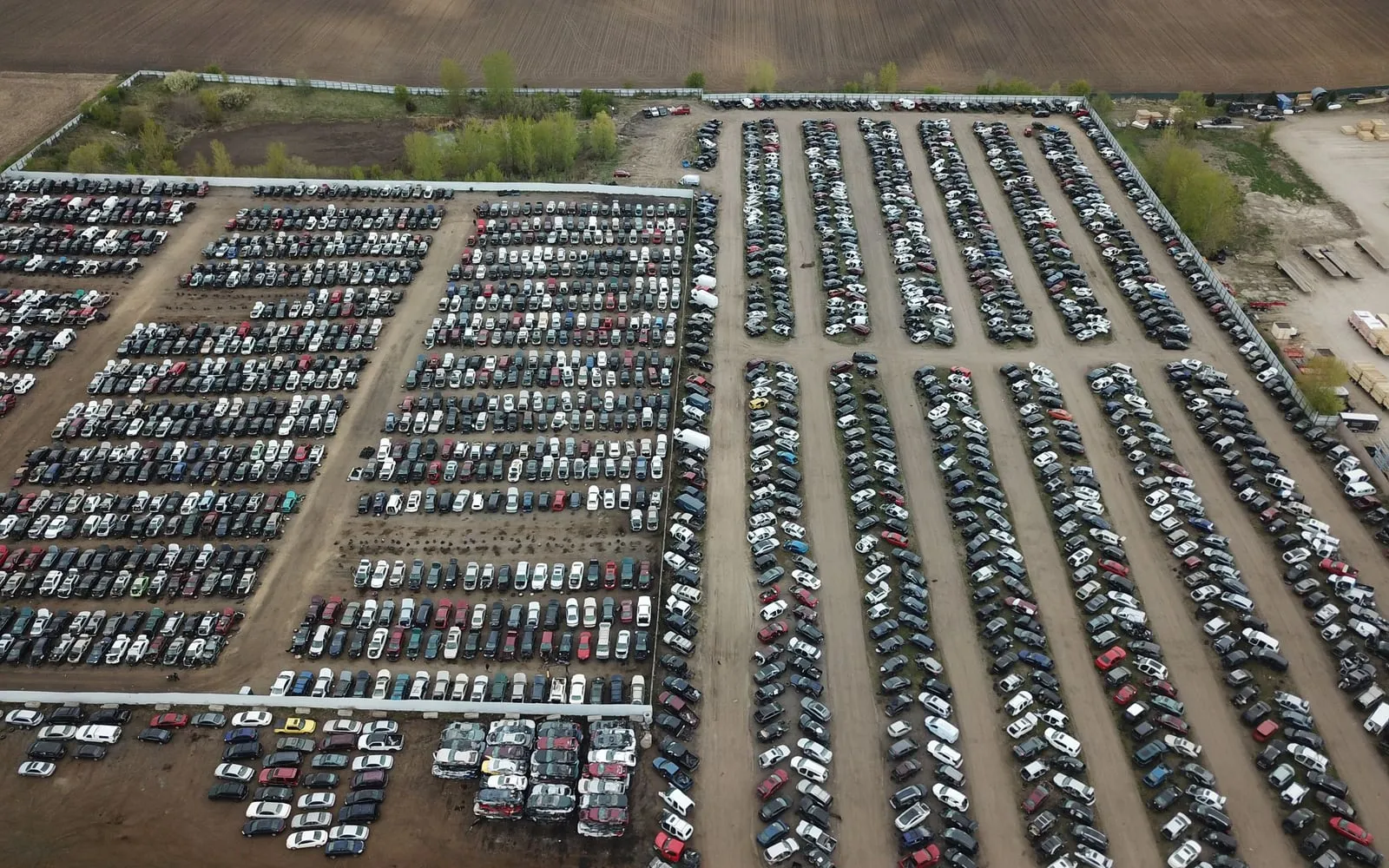 Aerial view of a large lot full of parked, retired vehicles in rows